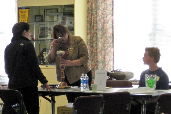 Lyme-Old Lyme High School’s History Club member Ian James (seated) looks on as Carol Brevard of Brevard Appraisal and Estate Services examines an antique lamp at the Old Lyme Historical Society’s antiques appraisal event “Vintage!” in March 2012.