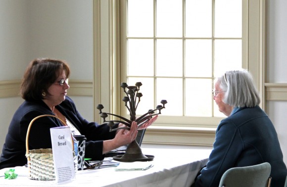 A member of the Old Lyme Historical Society looks on as Carol Brevard of Brevard Appraisal and Estate Services examines an antique candelabra at the Old Lyme Historical Society’s antiques appraisal event “Vintage!” in March 2013.