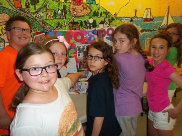 Student committee n front of display board, with Center School mural in background (left to right): John Coffey, Lizzy Duddy, Emily Nickerson, Anne Colangelo, Zoe Jensen, Elise DeBernardo, and Lauren Presti. (Missing from photo: Gabe Katwaru.)