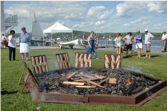 Connecticut River shad baking in front of fire on oak planks.