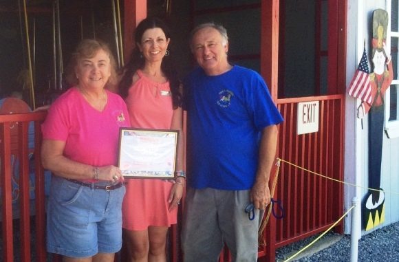 Craousel Shop owners Dee and Jerry stand in front of their business proudly displaying their Certificate of Appreciation from the OL Library.