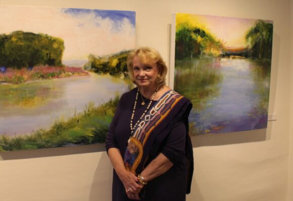 Jan Dilenschneider stands in front of a dyptych - a pair - of her paintings in the Sill House Gallery.